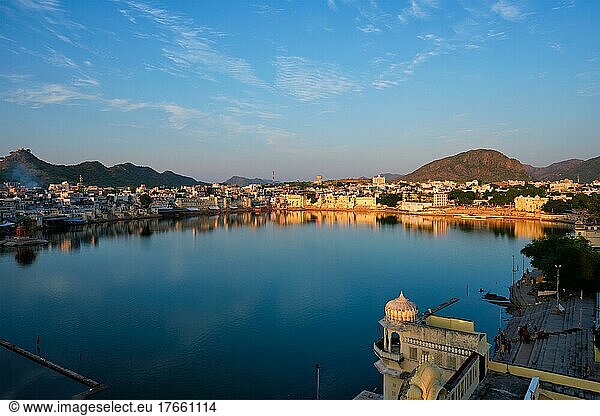 View of famous indian hinduism pilgrimage town sacred holy hindu religious city Pushkar amongst hills with Brahma mandir temple  lake and traditional Pushkar ghats at dusk sunset. Rajasthan  India