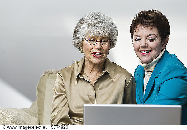 View of smiling business women sitting with a laptop.
