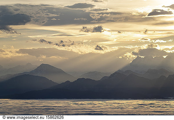 view of the Alps at sunrise  in the foreground Lake Geneva cloudy