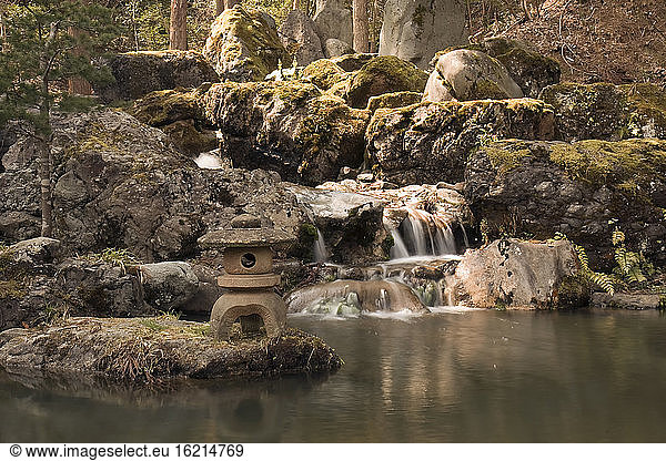 View of waterfall with stone lantern