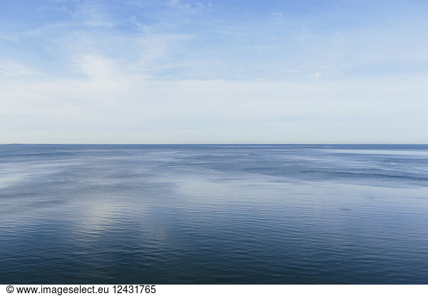 View out to the open sea from the coast. Flat calm water surface.