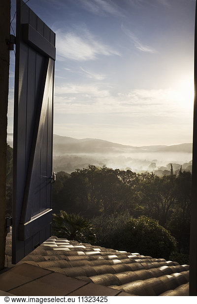 View through an open window  over a lake and mountain landscape.