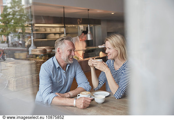 View through window of mature couple in coffee shop chatting