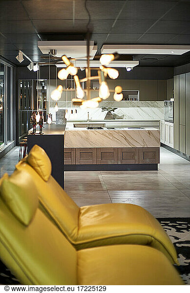 View to modern open plan kitchen with yellow leather chairs in the foreground