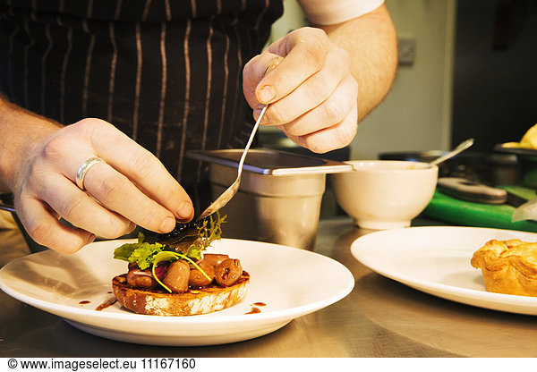 Village public house restaurant. A chef plating up a dish of meat and vegetables.