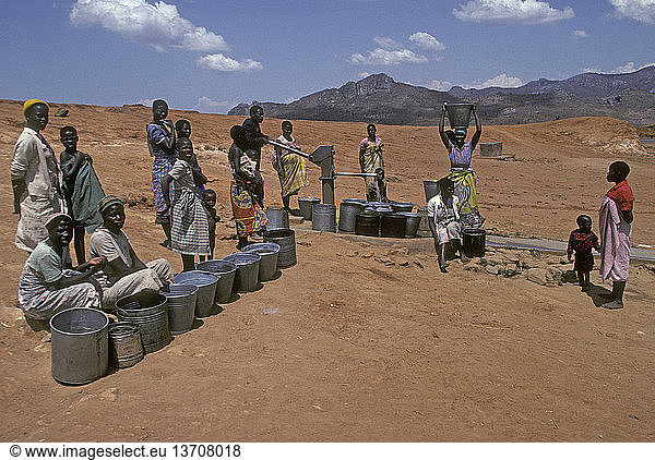 Villagers at a water pump and new borehole in Malawi  Africa.