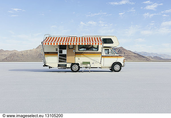 Vintage Dodge Sportsman RV with striped canopy parked on Salt Flats