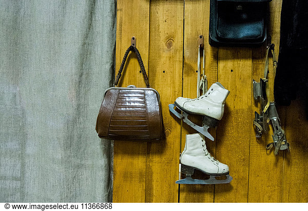 Vintage ice skates and handbag hanging from wooden wall