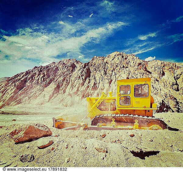 Vintage retro effect filtered hipster style travel image of Bulldozer doing road construction in Himalayas. Ladakh  Jammu and Kashmir  India  Asia