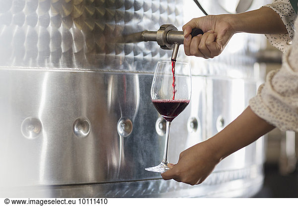 Vintner barrel tasting red wine from stainless steel vat