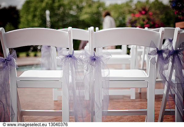 Violette Bänder auf leeren weißen Stühlen am Pool