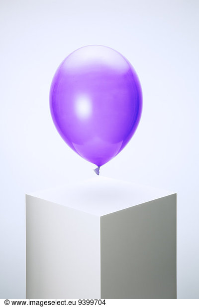 Violetter Ballon schwebt über dem Sockel
