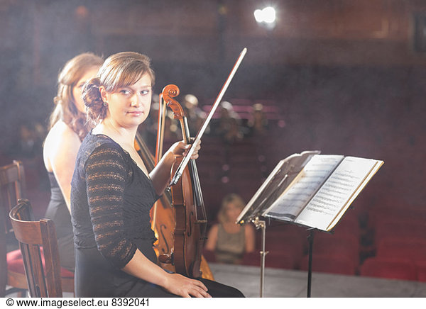 Violinists preparing for performance on theater stage