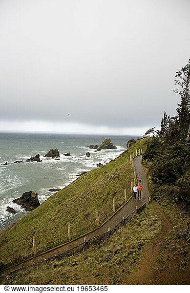 Visitors enjoy a paved trail overlooking the crashing waves on the edge of the steep Oregon coast.