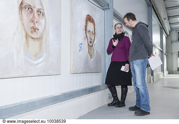 Visitors looking at paintings in an art gallery and discussing  Bavaria  Germany