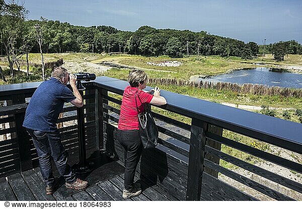 Visitors looking through mounted binoculars from the roof terrace in Zwin nature Park  bird sanctuary in Knokke-Heist  West Flanders  Belgium  Europe