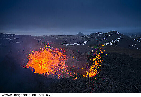 Volcanic terrain with burning hot lava in evening
