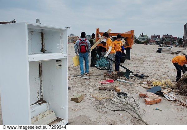 Volunteers armed with gloves  shovels and brooms clean up debris and sand deposited by Hurricane Sandy from the beach and boardwalk of the Brighton and Coney Island beach neighborhoods of New York The destructive Hurricane pushed tons of sand inland with. Volunteers armed with gloves  shovels and brooms clean up debris and sand deposited by Hurricane Sandy from the beach and boardwalk of the Brighton and Coney Island beach neighborhoods of New York The destructive Hurricane pushed tons of sand inland with its storm surge as well as carrying destroyed property onto the beach  some of it from the devastated Rockaway Peninsula Hundreds of volunteers organized by the NYC Mayor´s office performed a day of service helping people in Brooklyn  Staten Island and Rockaway