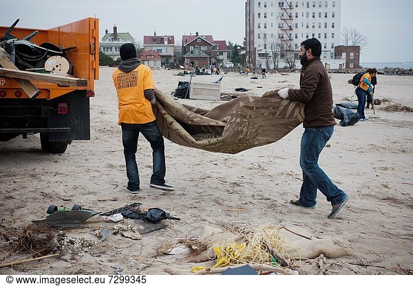 Volunteers armed with gloves  shovels and brooms clean up debris and sand deposited by Hurricane Sandy from the beach and boardwalk of the Brighton and Coney Island beach neighborhoods of New York The destructive Hurricane pushed tons of sand inland with. Volunteers armed with gloves  shovels and brooms clean up debris and sand deposited by Hurricane Sandy from the beach and boardwalk of the Brighton and Coney Island beach neighborhoods of New York The destructive Hurricane pushed tons of sand inland with its storm surge as well as carrying destroyed property onto the beach  some of it from the devastated Rockaway Peninsula Hundreds of volunteers organized by the NYC Mayor´s office performed a day of service helping people in Brooklyn  Staten Island and Rockaway