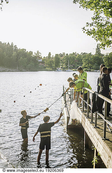 Volunteers cleaning plastic from lake against sky