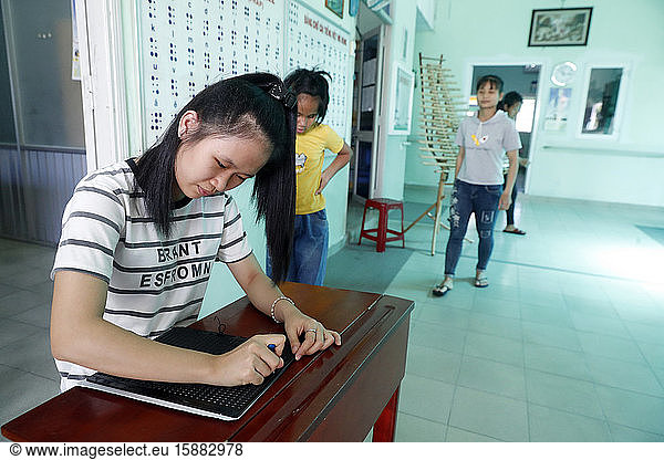 Von Children Action geleitetes Zentrum für blinde Kinder. Mädchen schreibt Blindenschrift. Ho Chi Minh Stadt. Vietnam.
