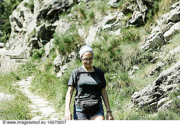 Vorderansicht einer lächelnden Wanderin auf einem Bergpfad