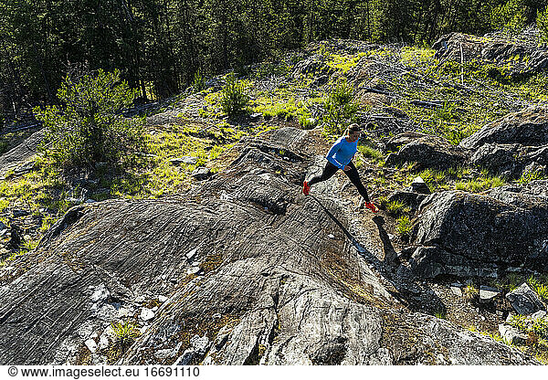 Vorderansicht einer starken Sportlerin  die beim Fitnesstraining auf dem Lande einen Bergpfad hinaufläuft