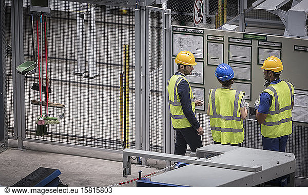 Vorgesetzter und Arbeiter prüfen Informationen an der Wand in der Fabrik