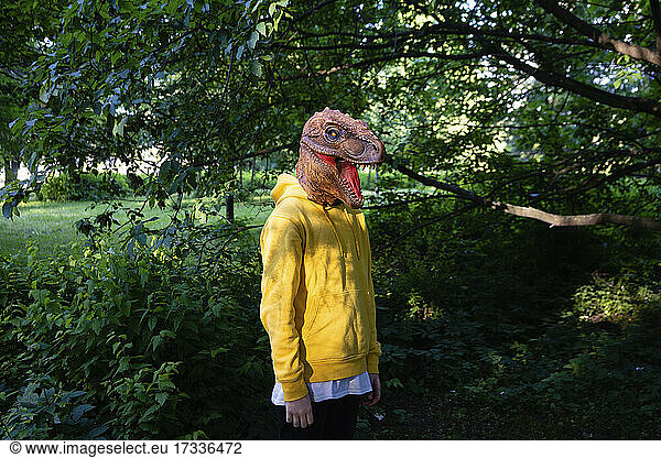 Vorpubertärer Junge mit Dinosauriermaske