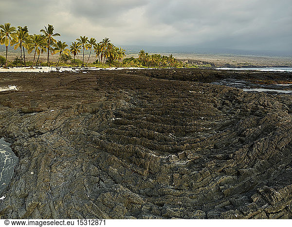 Vulkanische Felsen und Bäume im Puuhonua O Honaunau National Historical Park gegen bewölkten Himmel
