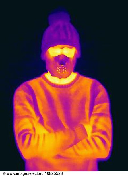 Wärmebild eines Mannes mit gekreuzten Armen  der eine bedrohliche Maske und eine Strickmütze trägt.