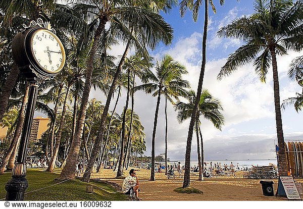 Waikiki Beach Clock Palm Trees Honolulu Oahu Hawaii. O'ahu. Hawaii. Das weltberühmte Viertel Waikiki an der Südküste von Honolulu war einst ein Spielplatz für die hawaiianischen Könige. Waikiki  auf Hawaii als sprudelnde Gewässer bekannt  wurde der Welt vorgestellt  als 1901 das erste Hotel  das Moana Surfrider  an seinen Ufern gebaut wurde. Heute ist Waikiki das wichtigste Hotel- und Feriengebiet Oahus und ein pulsierender Treffpunkt für Besucher aus aller Welt. Entlang des Hauptstreifens der Kalakaua Avenue finden Sie erstklassige Einkaufsmöglichkeiten  Restaurants  Unterhaltungsangebote  Aktivitäten und Resorts. Waikiki ist vor allem für seine Strände bekannt  und jedes Zimmer ist nur zwei oder drei Blocks vom Meer entfernt. Mit Leahi (Diamond Head) als Kulisse sind die ruhigen Gewässer von Waikiki wie geschaffen für eine Surfstunde. Der legendäre hawaiianische Wassersportler Duke Kahanamoku wuchs mit dem Surfen in den Wellen von Waikiki auf. Dieser olympische Goldmedaillengewinner im Schwimmen brachte den Besuchern um die Jahrhundertwende das Surfen bei und wurde später als ? Der Vater des modernen Surfens. Heute führen die Waikiki Beach Boys das Vermächtnis von Duke fort  indem sie Besuchern das Surfen und Kanufahren beibringen  und die Duke Kahanamoku-Statue ist zu einem Wahrzeichen von Waikiki geworden.