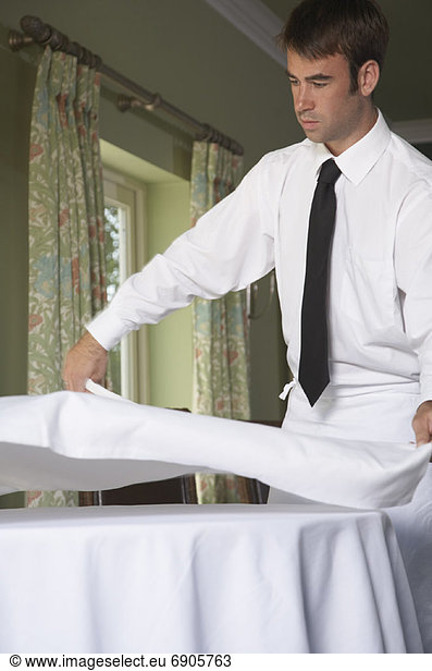 Waiter Putting Tablecloth on Table