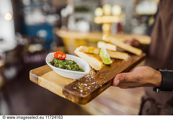 Waiter serving bread with pesto sauce
