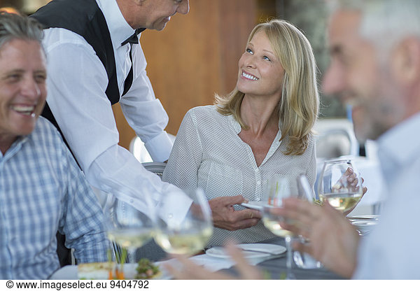 Waiter serving food to woman in restaurant