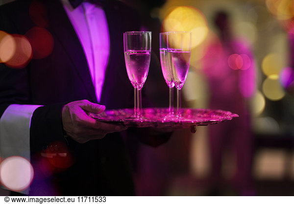 Waiter with tray serving champagne glasses on a party