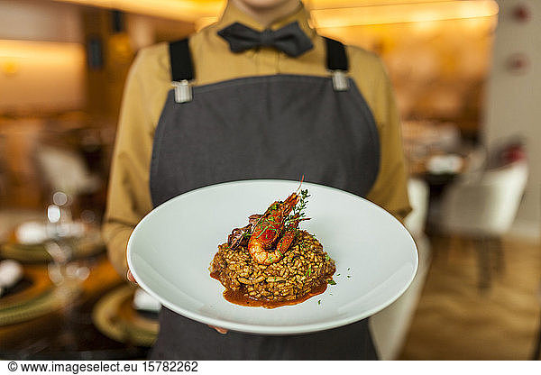 Waitress serving paella on white plate