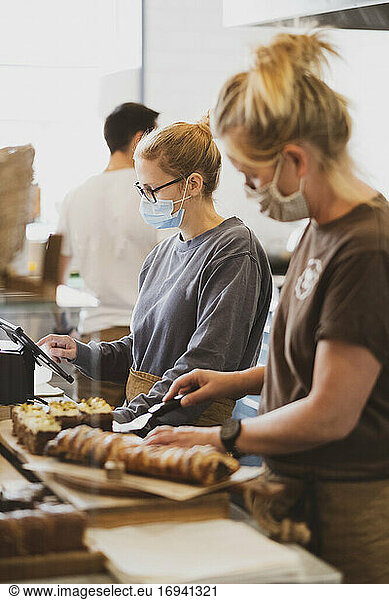 Waitress wearing face mask working in a cafe preparing food.