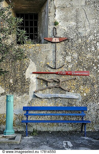 Wall decoration of nautical symbols on old house wall  small anchor  paddle of rowing boat  sailor's knot  ship's plank  bench painted blue underneath  harbour of Portoferraio  Elba  Tuscany  Italy  Europe
