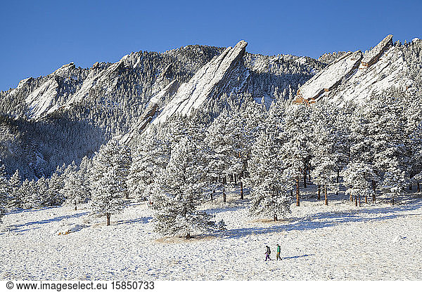 Wanderer überqueren Schneewiese unterhalb von Flatirons oberhalb von Boulder  Colorado
