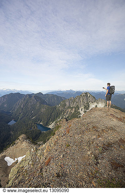 Wanderer fotografiert in voller Länge  während er auf einer Klippe gegen den Himmel steht