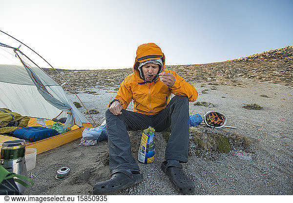 Wanderer genießt eine Mahlzeit neben seinem Zelt.