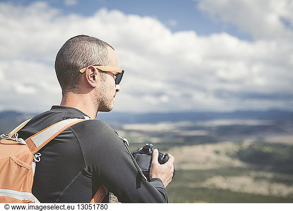 Wanderer hält Kamera beim Blick in die Landschaft