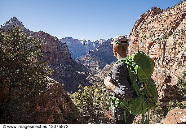 Wanderer mit Rucksack beim Anblick von Felsformationen in der Wüste