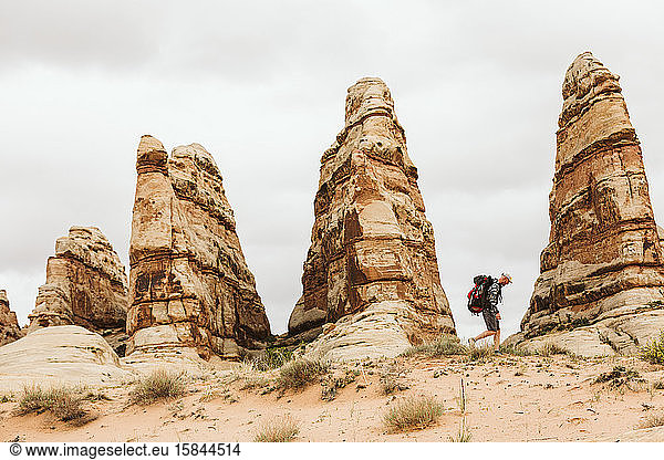 Wanderer mit Rucksack wandert neben Türmen aus rotem Sandstein in der Wüste von Utah