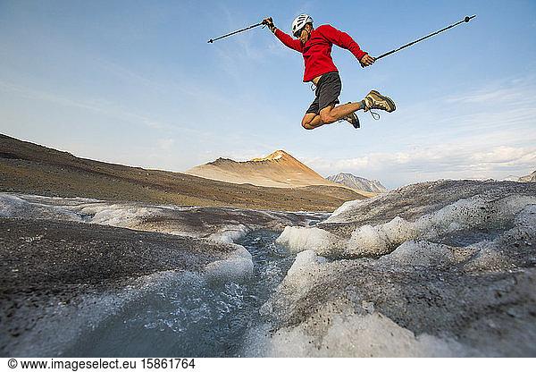 Wanderer springt über Gletscherbach.