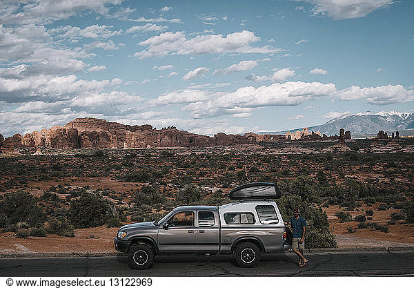 Wanderer steht mit dem Auto auf der Straße im Arches-Nationalpark