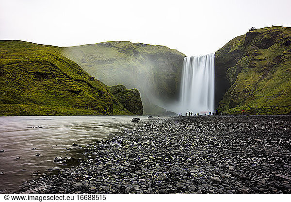 Wanderer unter dem berühmten isländischen Wasserfall Skogafoss.