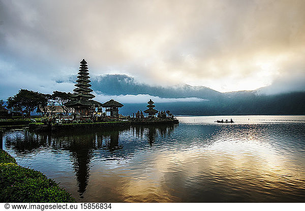 Watching a sunrise in Bali at a Hindu Temple while a canoe cross a lak