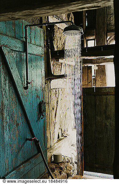 Water flowing through shower mounted on old wooden wall